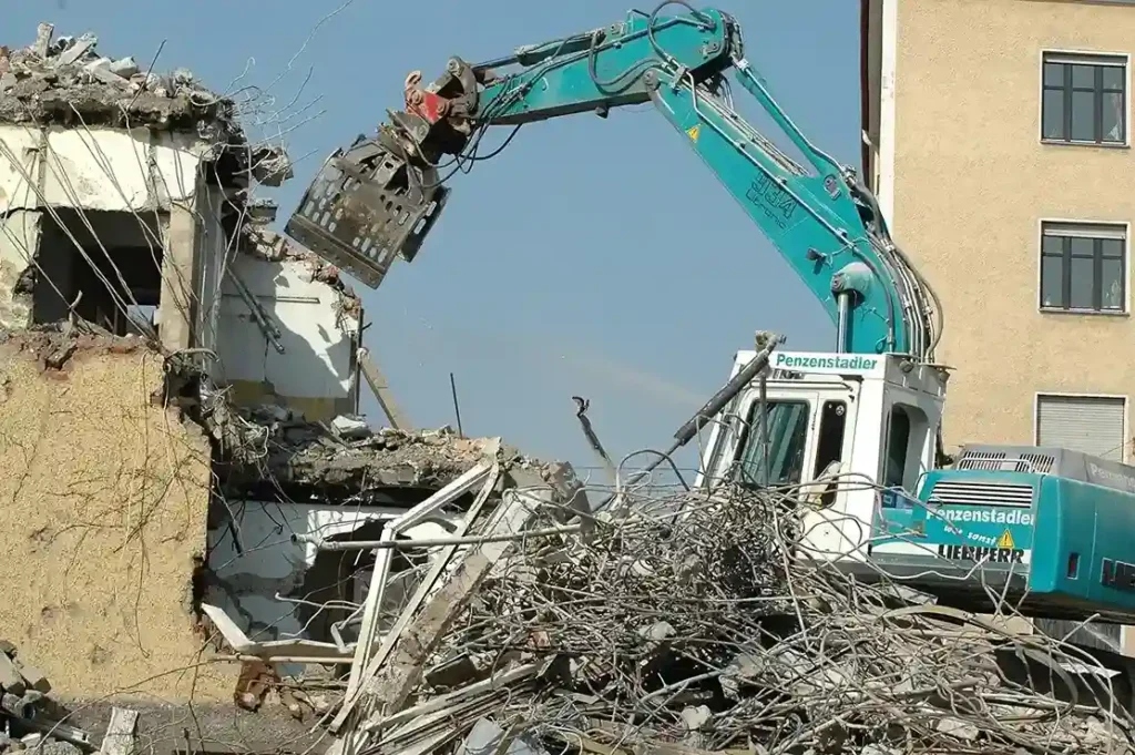 Blue green excavator demolishing a building